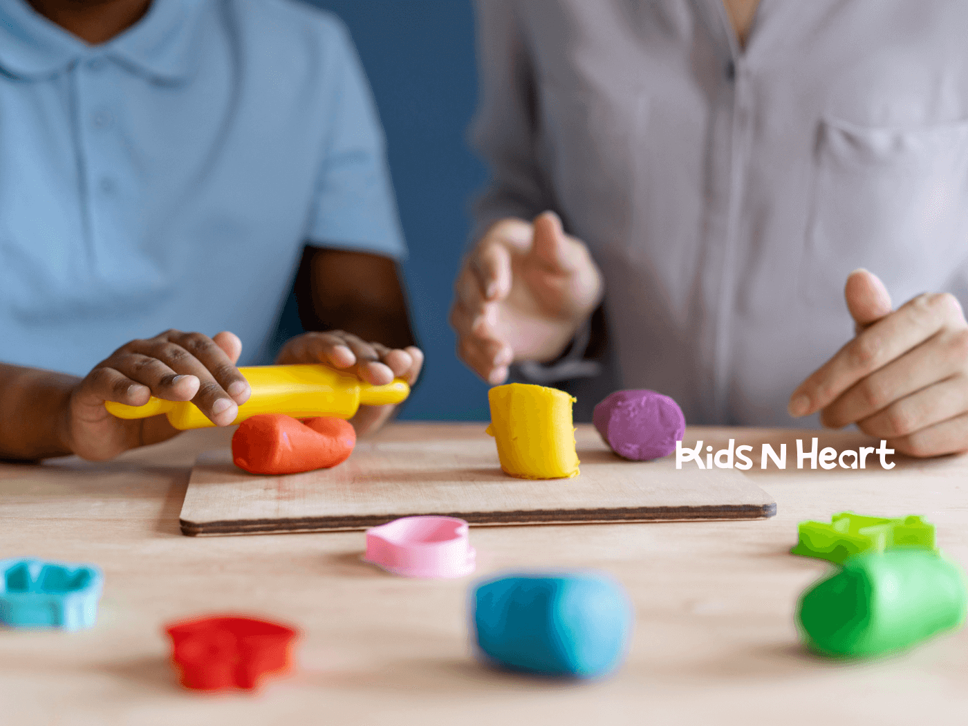 Child and therapist shape colorful playdough together, practicing fine motor skills during a hands-on therapy activity.