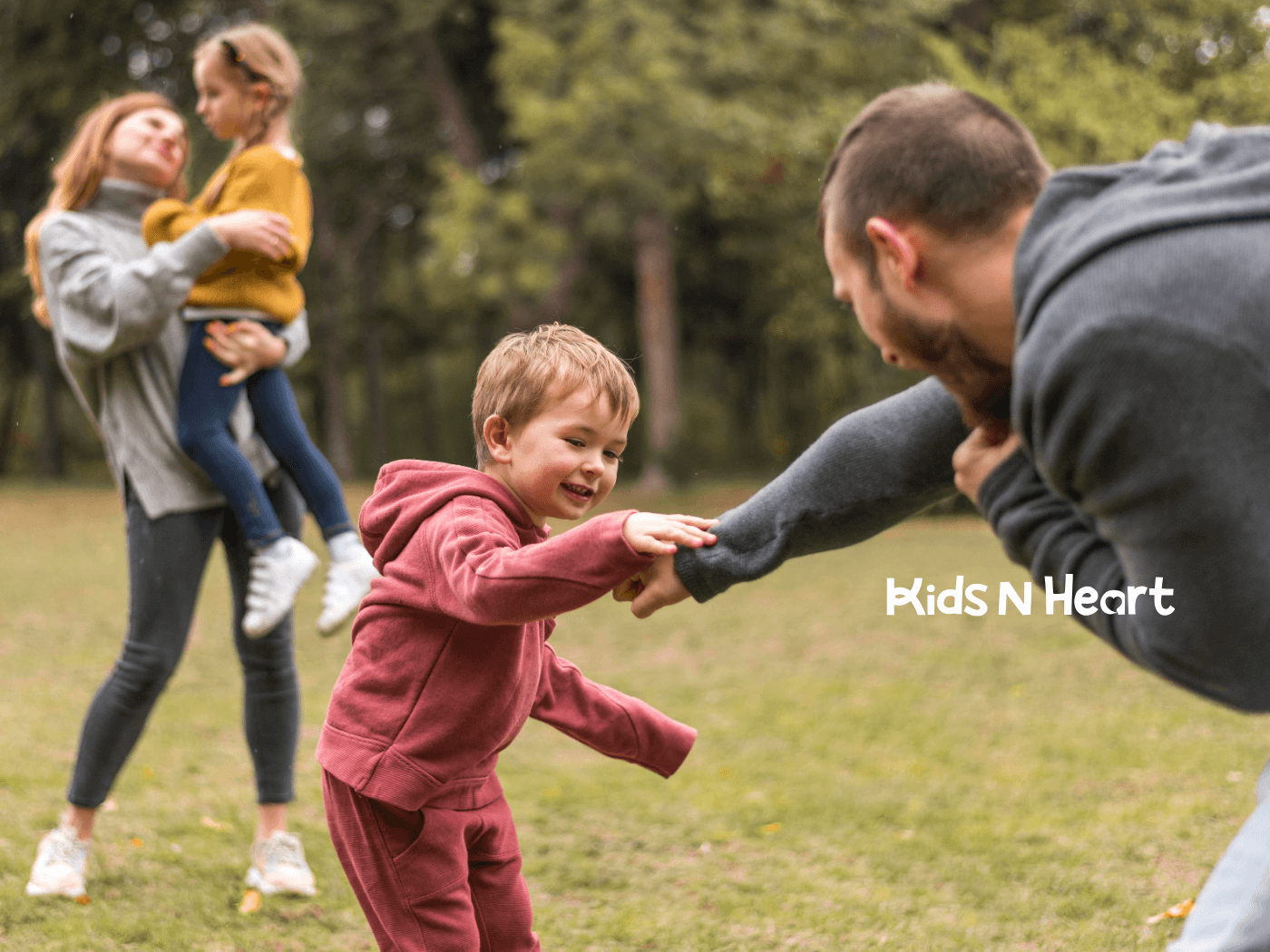 Parents play with young children outdoors, encouraging bonding, movement, and social interaction in a park setting.