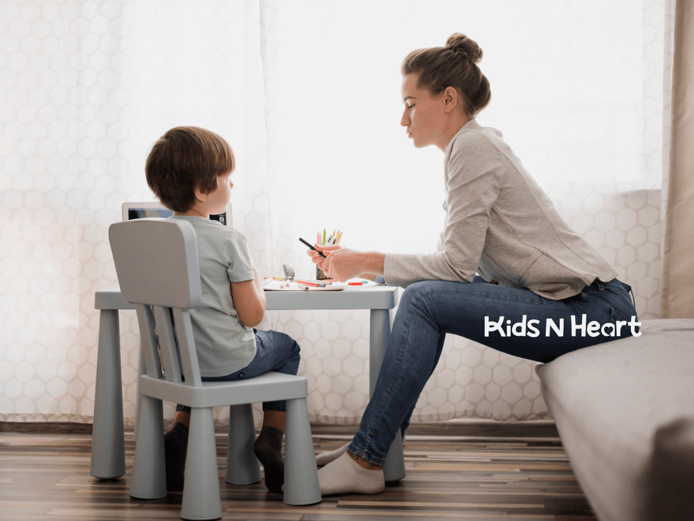 ABA therapist sits at a small table, guiding a young child through drawing or learning activities in a calm home setting.