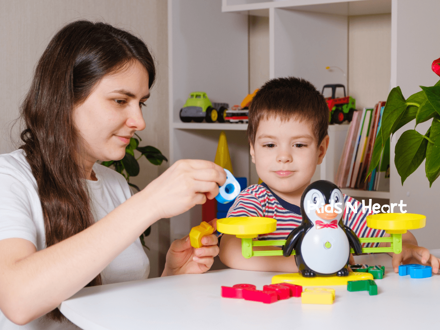Therapist helps young child practice balance and fine motor skills using a colorful toy scale during learning session.