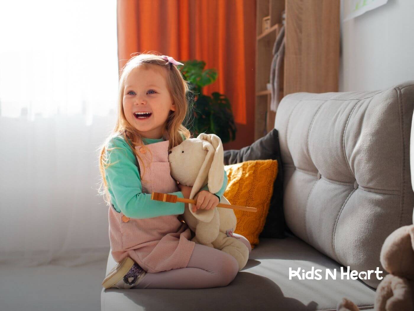 Smiling girl holding a stuffed bunny on a couch in ABA therapy.