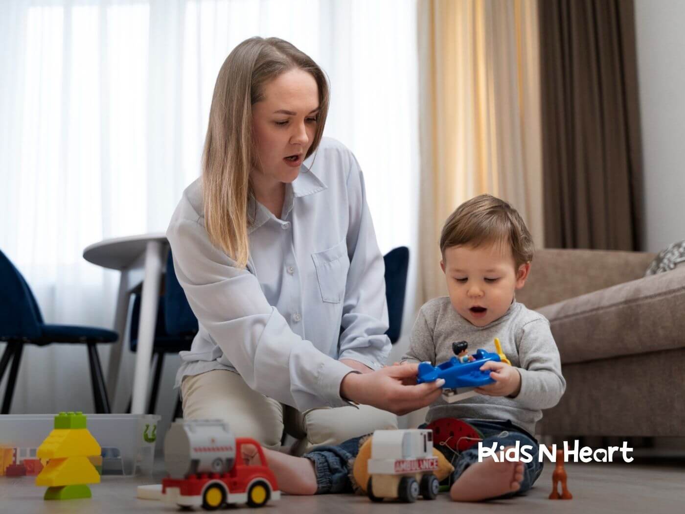 BCBA playing with a toddler and toy vehicles on the floor in ABA therapy.