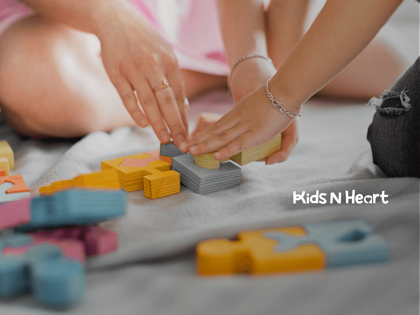 An autistic child and RBT stacking colorful puzzle pieces together on floor during in-home ABA therapy in NC.