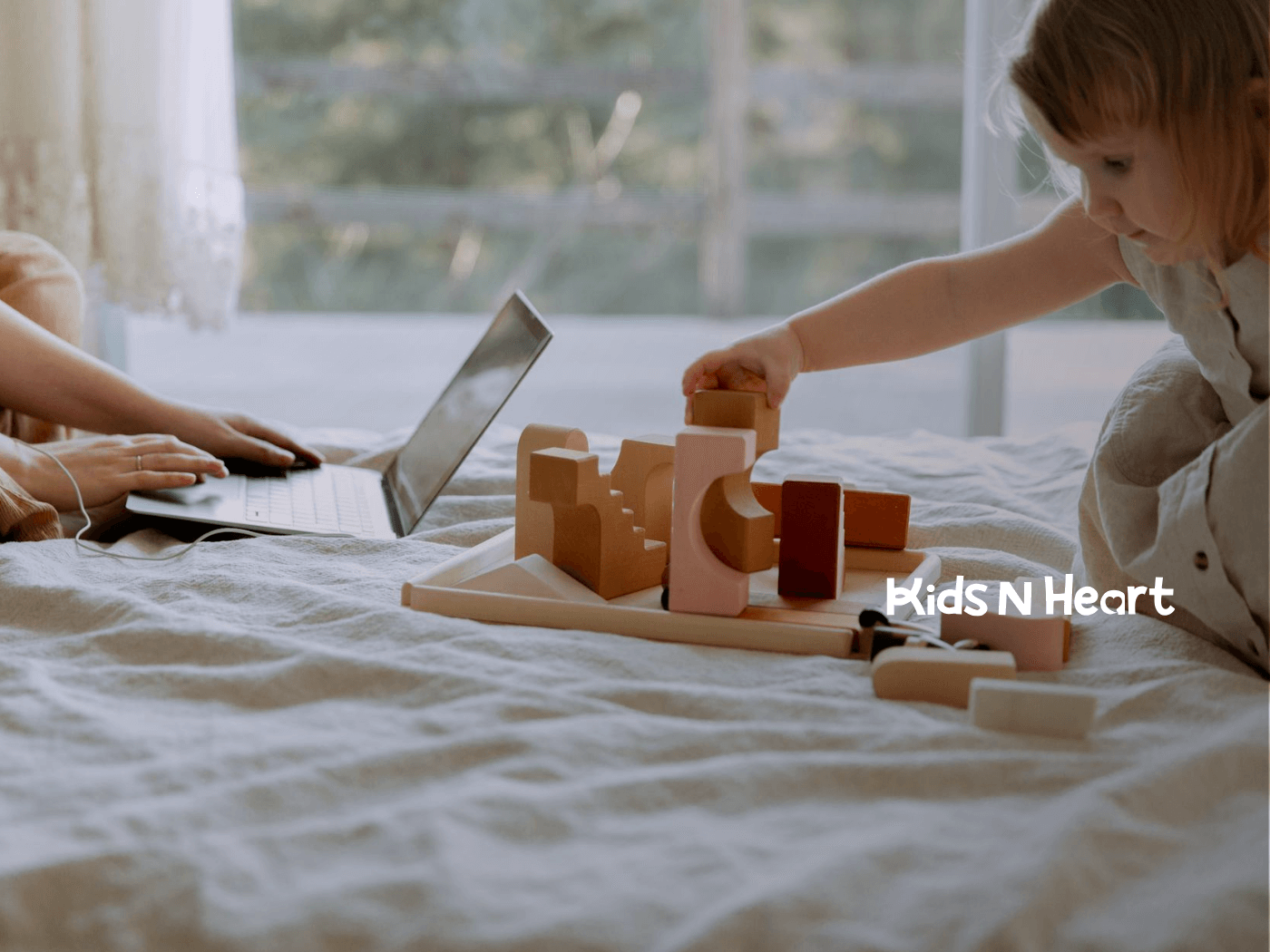 An autistic child building with wooden blocks while an ABA therapist types on a laptop during ABA therapy in NC.