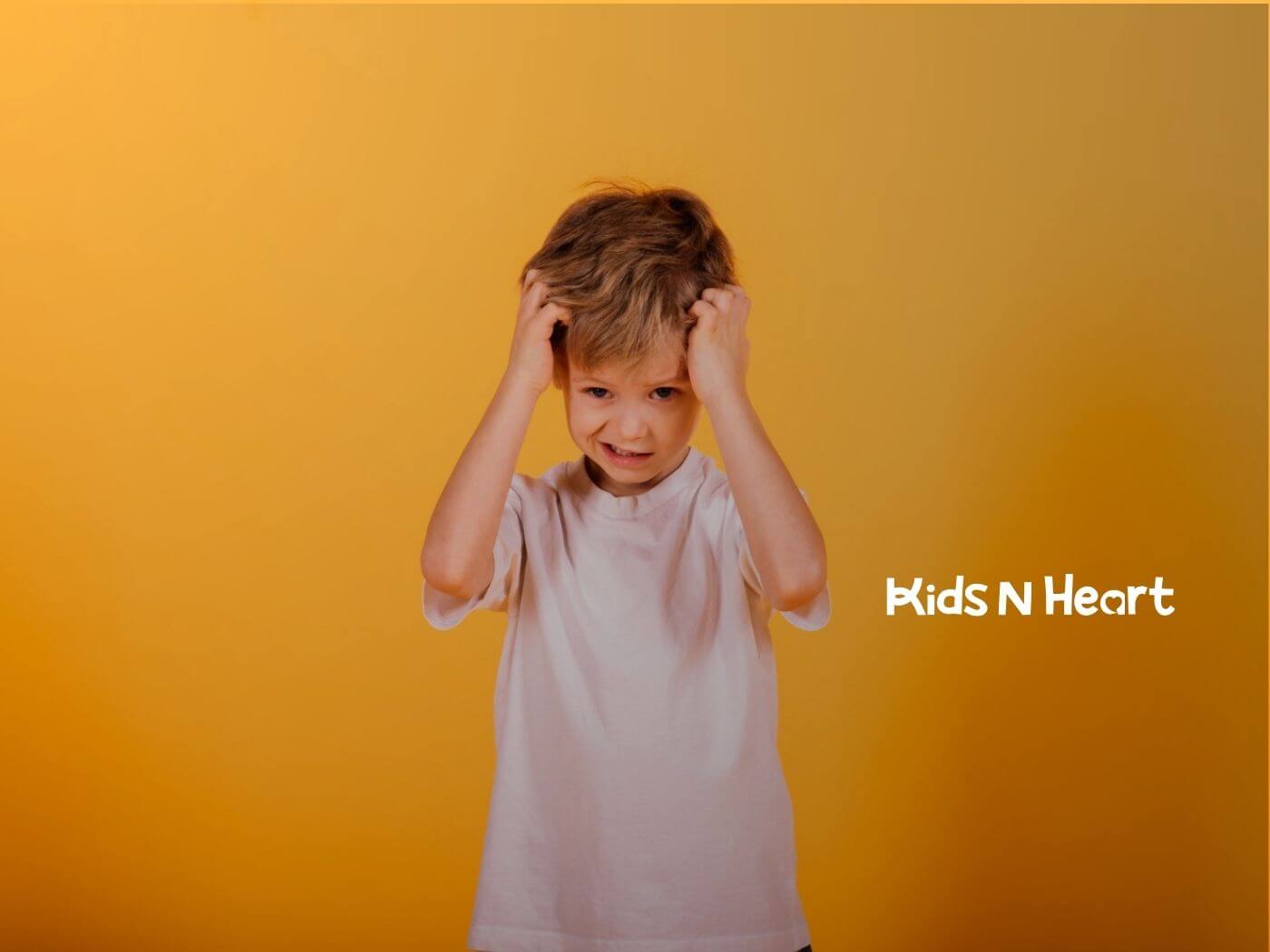 A boy with autism holding his head with both hands, looking upset.