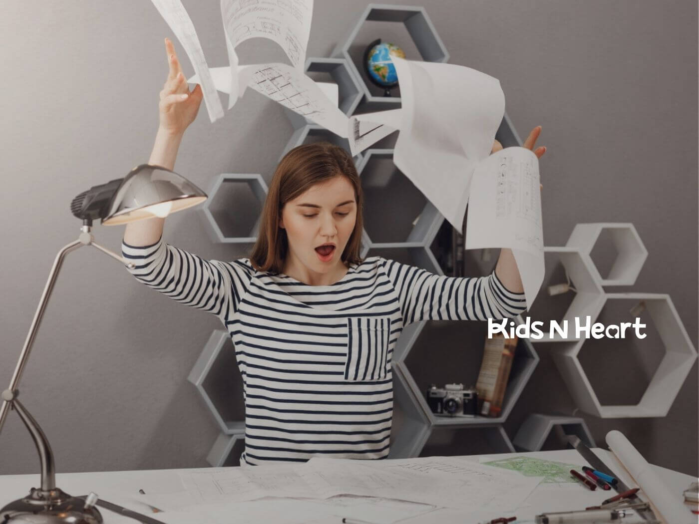Frustrated woman throwing papers into the air at her desk.