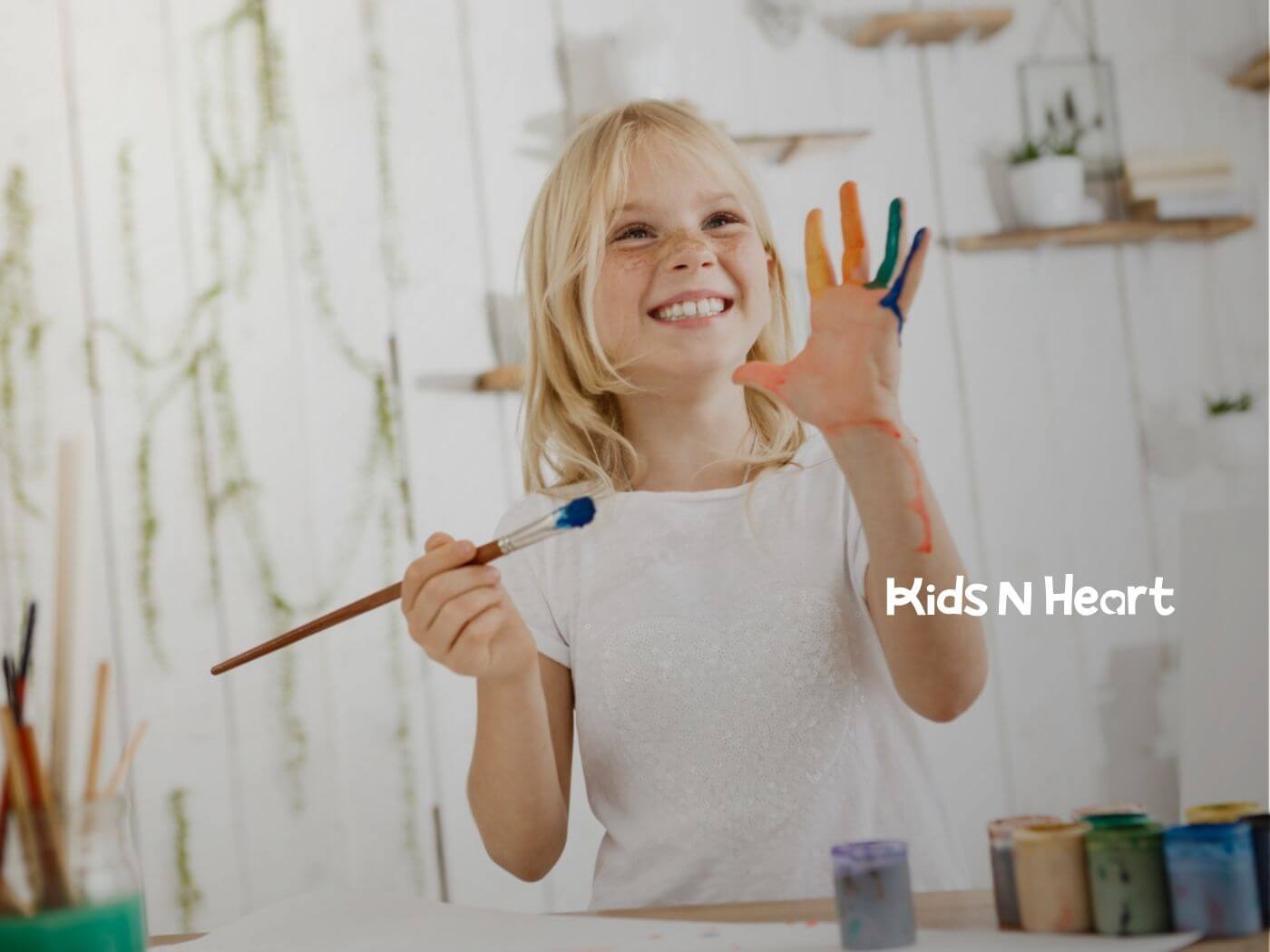 Smiling girl painting with colorful paint on her hand in ABA therapy.