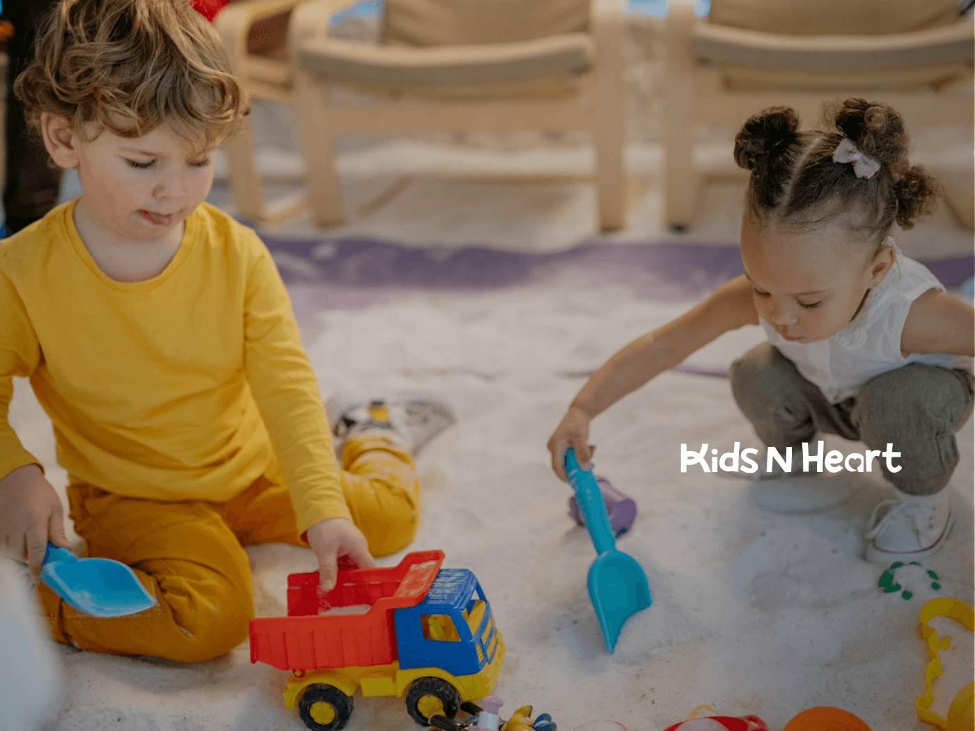 Two autistic children playing in sand with toy truck and shovels during in-home ABA therapy in North Carolina.