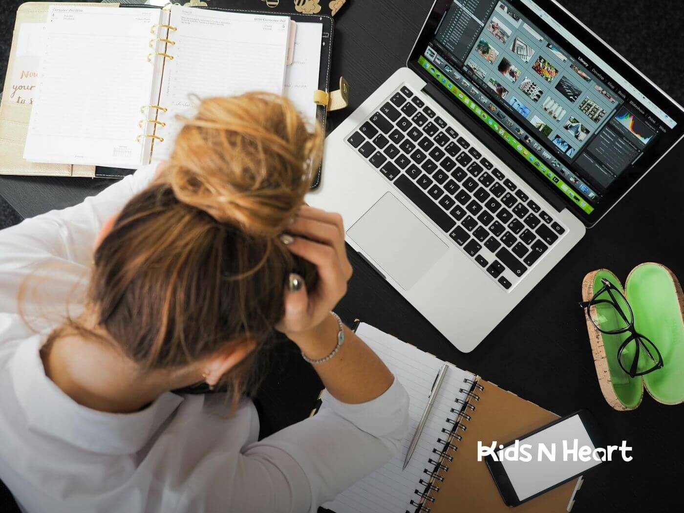Autistic woman holding her head in frustration while working on a laptop at a cluttered desk in North Carolina.