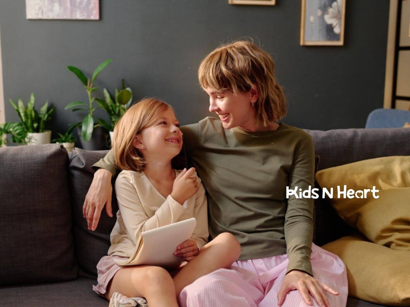 Therapist and girl with autism smile together on a couch at home during ABA therapy.