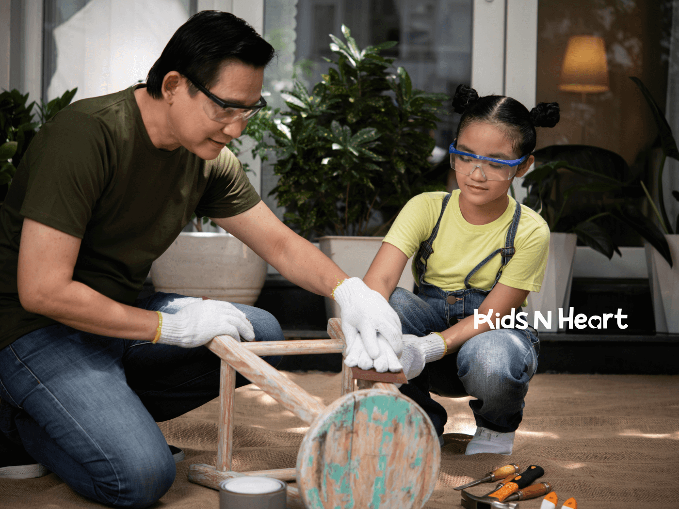 A male therapist and autistic girl working on a DIY project, sanding a chair together at home during ABA therapy.