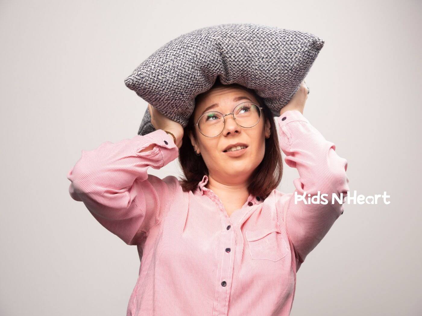 BCBA holding a pillow on her head with a tired expression.