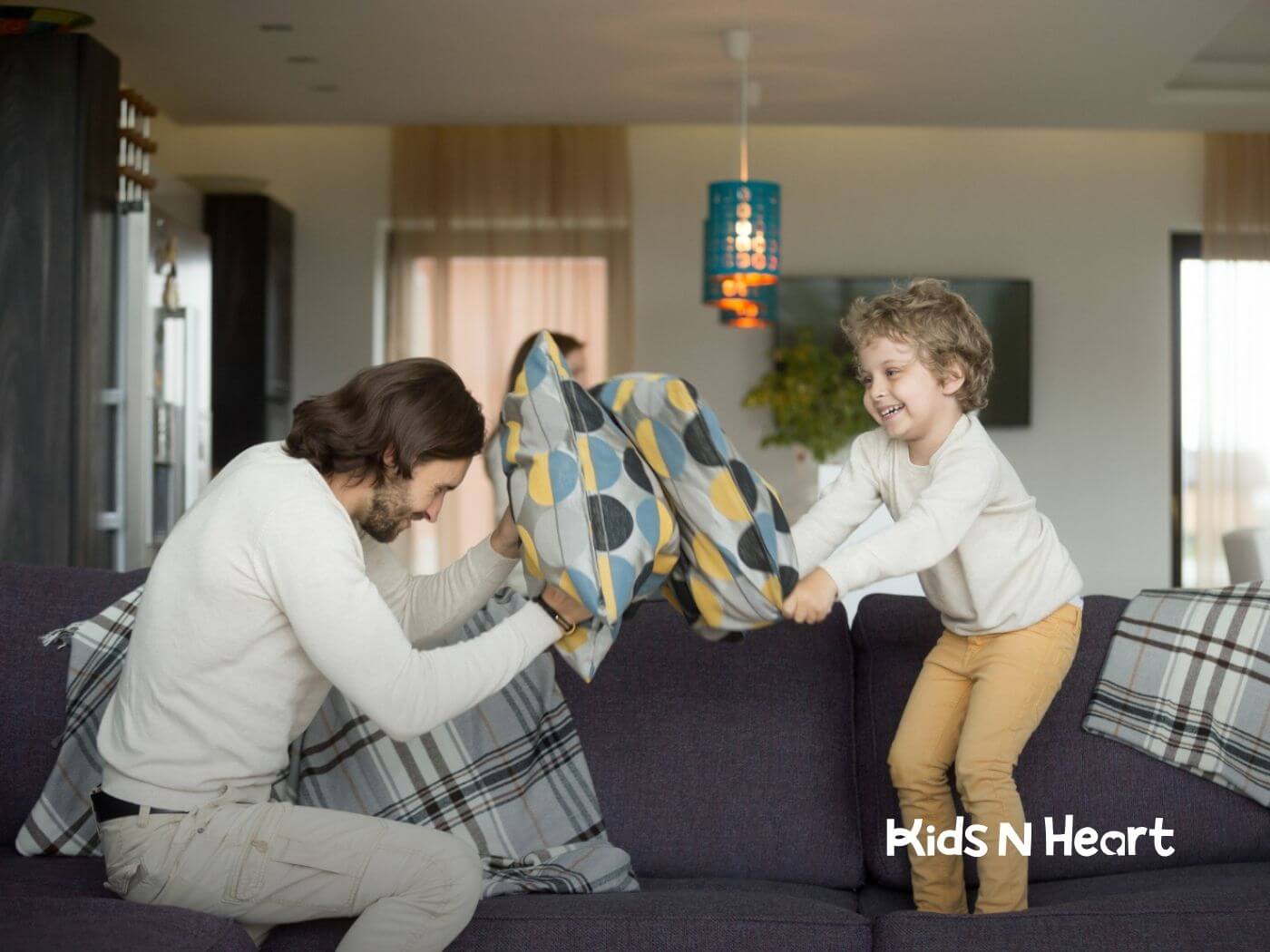 Male BCBA and autistic child having a playful pillow fight on a couch during ABA therapy.
