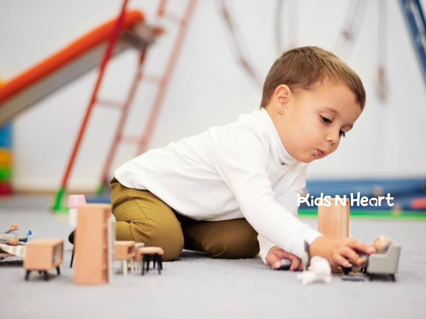 Young boy playing intently with small toys on the floor during ABA therapy.