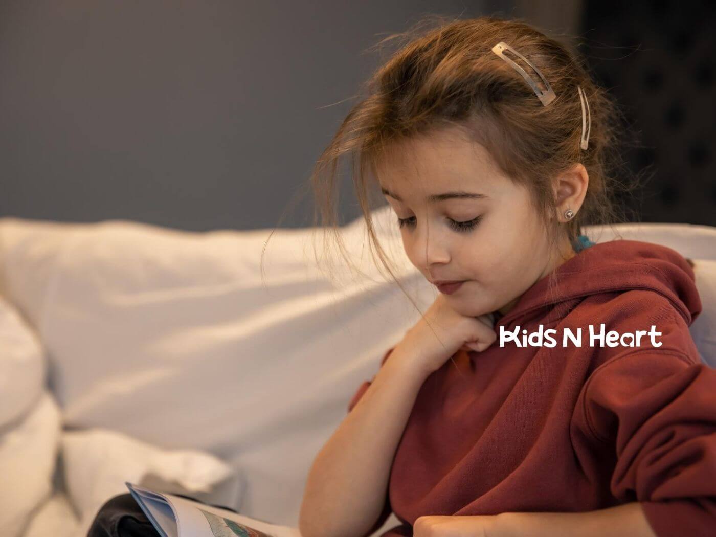 Young girl with autism reading a book on a couch during ABA therapy.