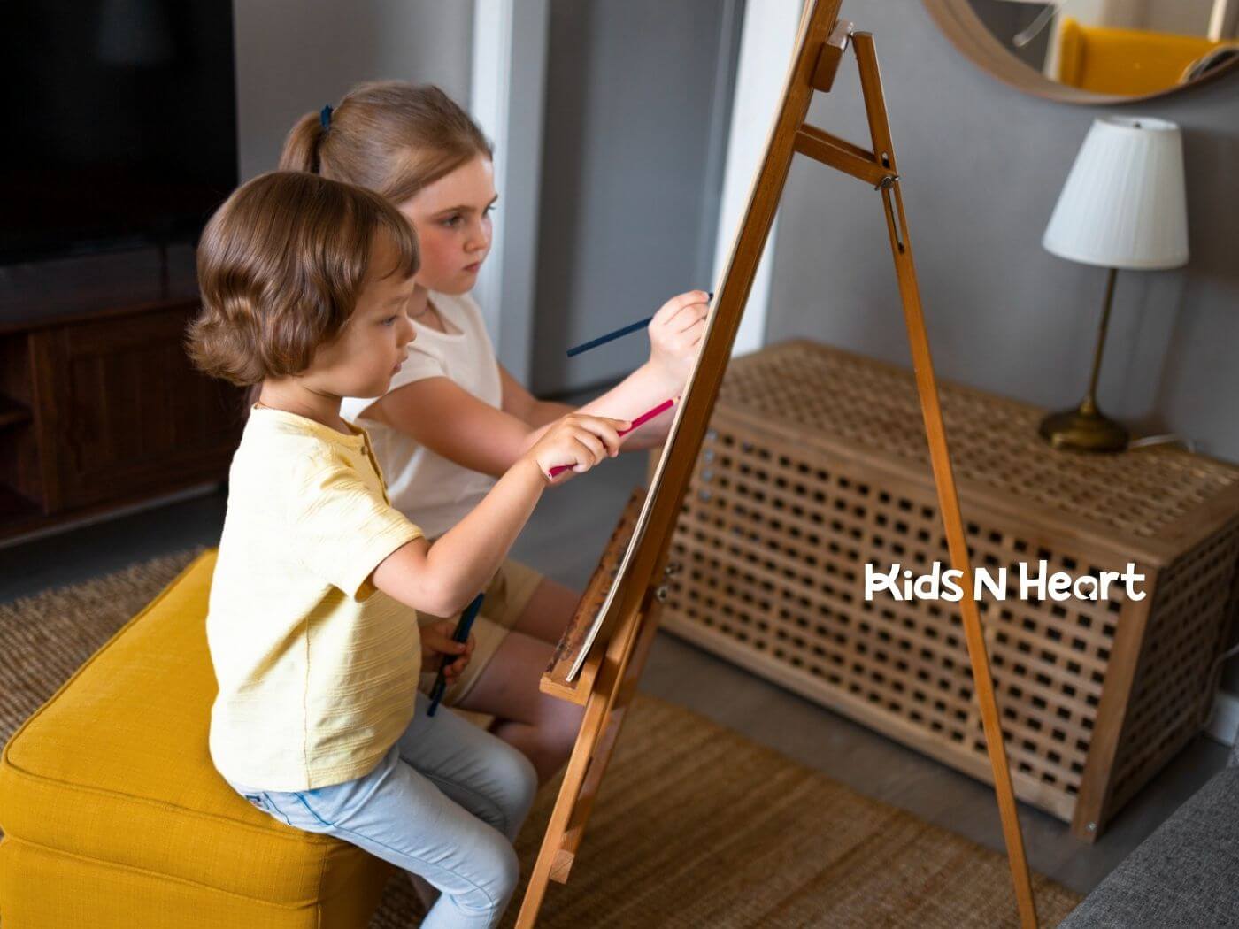 Two young children sitting on a yellow cushion, drawing together in ABA therapy.