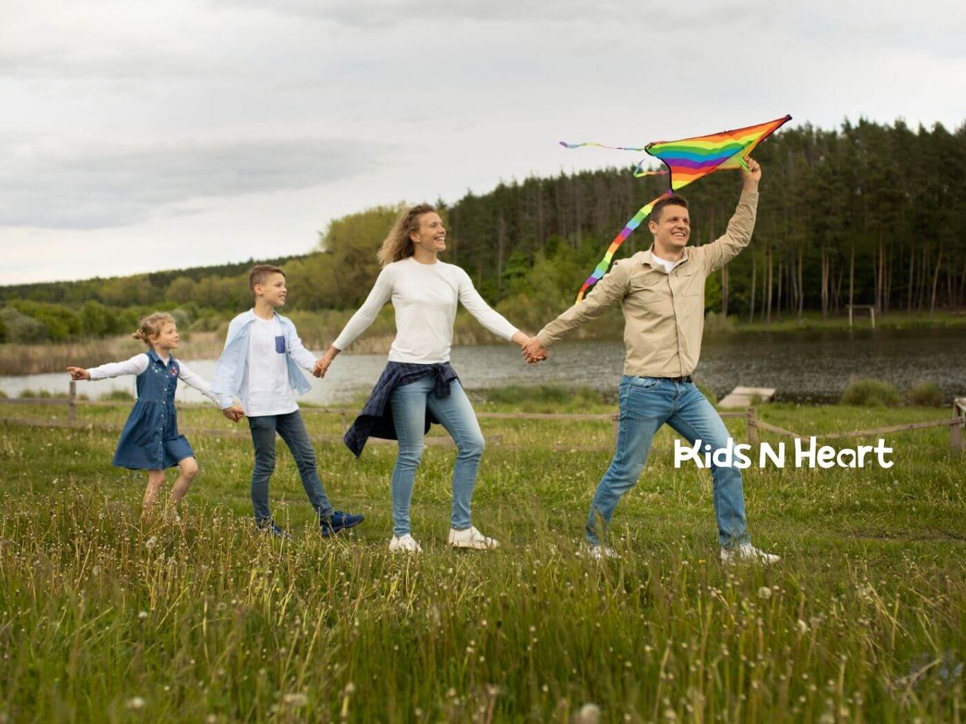 Family holding hands outdoors while flying a colorful kite.
