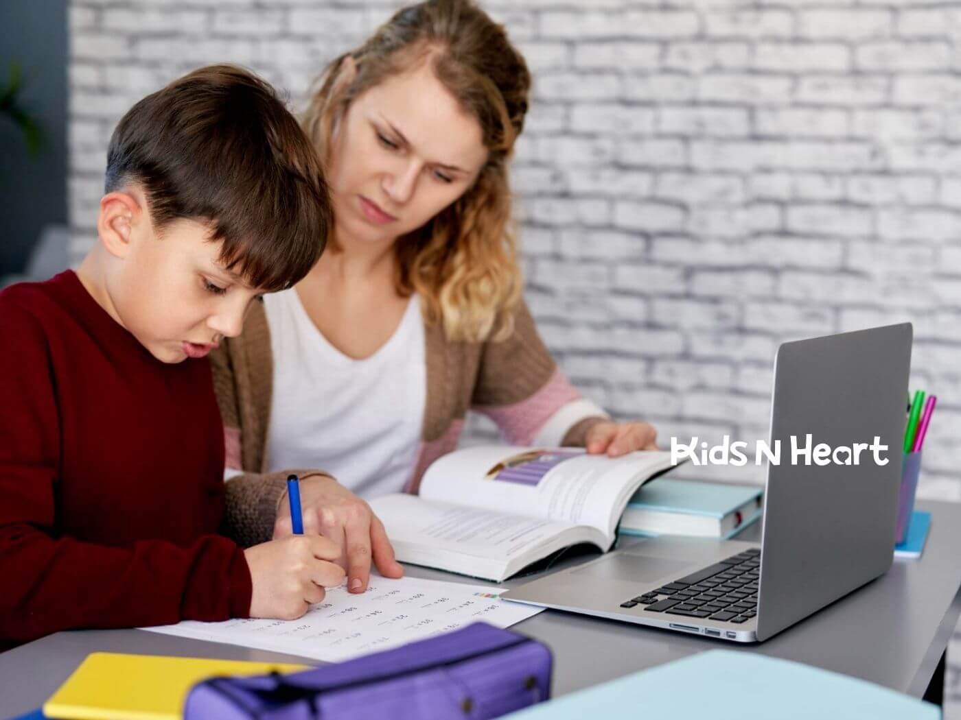 BCBA helping her an autistic boy with homework at a desk during ABA therapy.