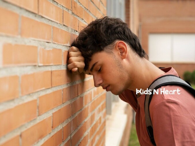 Autistic teenager with a backpack leaning against a wall, looking stressed.