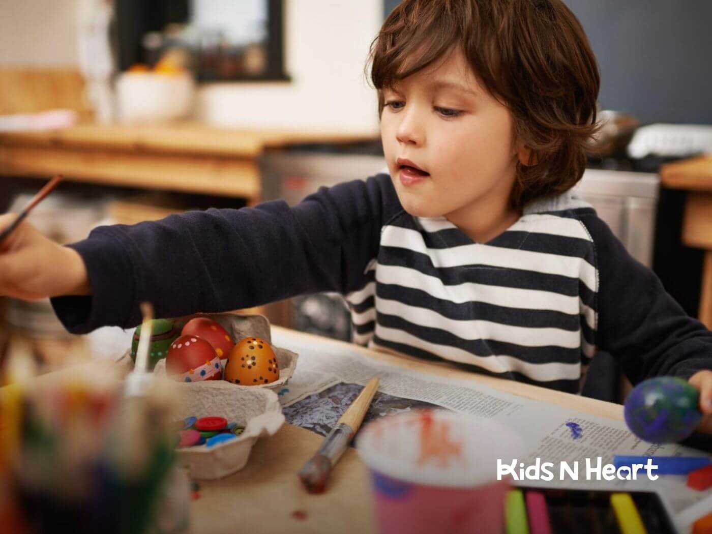 Child with autism painting decorative eggs at a table during ABA therapy.