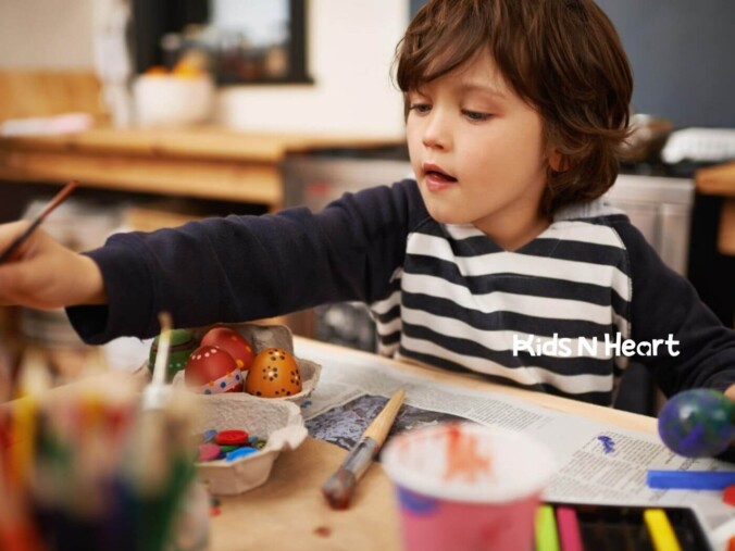 Child with autism painting decorative eggs at a table during ABA therapy.