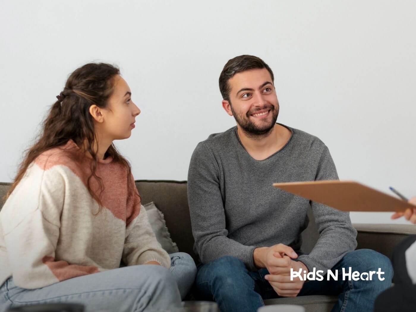 Couple sitting on a couch smiling during ABA parent training session.