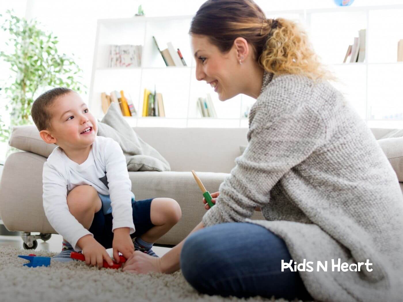 BCBA playing on the floor with a young child in a bright living room.