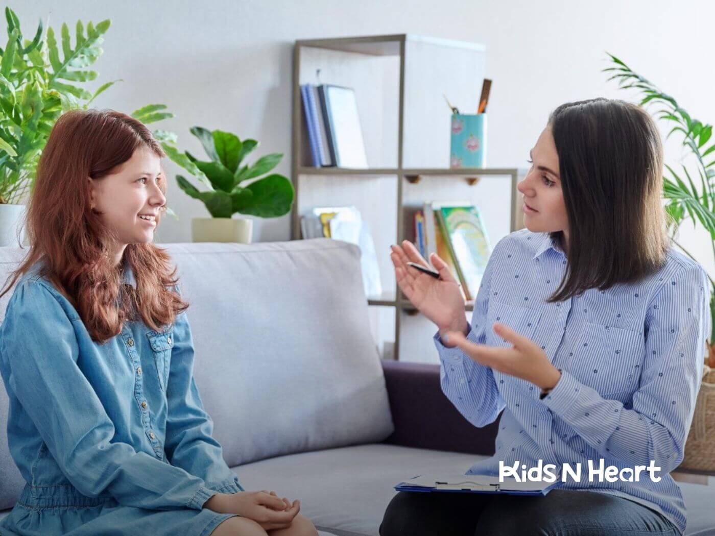 A BCBA talking with a teenage girl on a couch during a session.